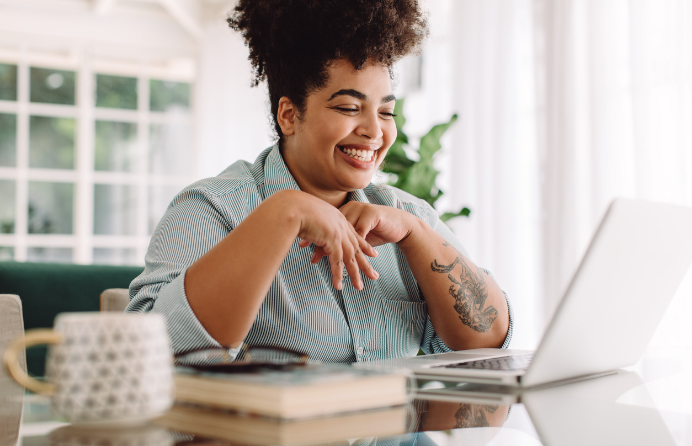 Woman sitting at laptop while smiling.